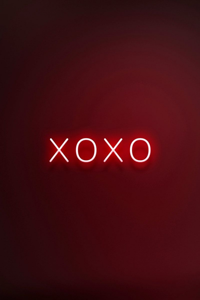 Glowing XOXO neon typography on a red background  free image by